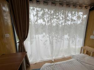 a bedroom with a window with a tree at Fish Farm Uncle Thanh in Xóm Soi (1)