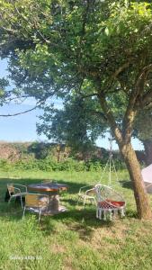 a picnic table and a swing under a tree at tente western in Le Pener +4 photos