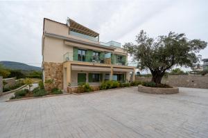 a large house with a tree in front of it at Asini deluxe suite 2, with rooftop terrace and breathtaking views in Asíni