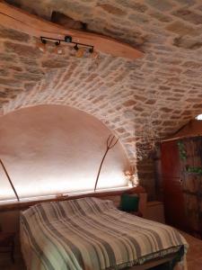 a bed in a room with a brick wall at Studio l'envoûté in Saint-Rome-de-Tarn