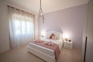 a white bedroom with a bed with pink bows at Deledda Rooms Boutique in Budoni