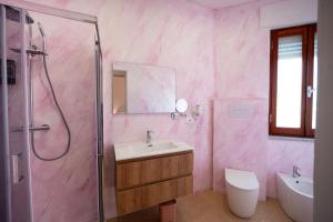 a pink bathroom with a sink and a shower at Deledda Rooms Boutique in Budoni +70 photos
