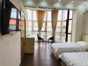 a hotel room with two beds and a desk with chairs at Soro Hotel in Dushanbe
