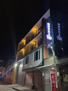 a building with a neon sign on the side of it at Hotel Olam Confort in Villavicencio