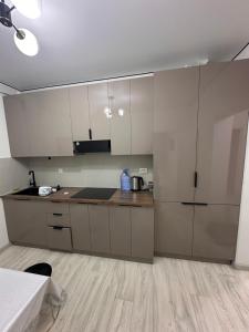 a kitchen with white cabinets and a wooden floor at 7 Su Nury in Almaty