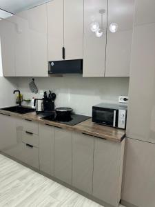a kitchen with white cabinets and a black microwave at 7 Su Nury in Almaty