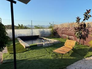 a bench sitting in the grass next to a pond at Cabaña rural con piscina privada in Orihuela