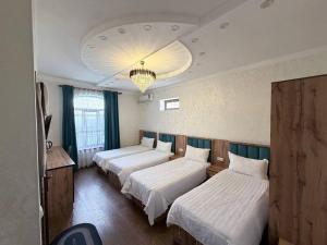 a hotel room with three beds and a chandelier at Soro Hotel in Dushanbe