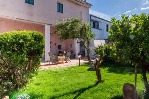 a yard with green grass and a building at Deledda Rooms Boutique in Budoni