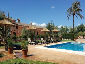 a pool with chairs and umbrellas next to a house at Agroturismo Finca Son Sala in Campos