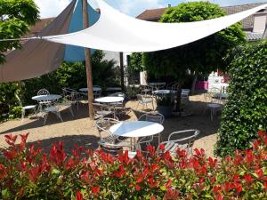 a group of tables and chairs under a white umbrella at Logis Hôtel Le Merle Blanc in Digoin