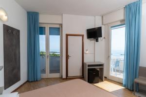a bedroom with a bed with blue curtains and a balcony at Hotel Concord in Lido di Savio