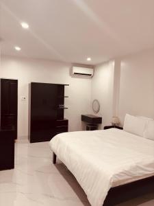 a bedroom with a white bed and a black cabinet at A T Homestay in Thôn Dương Xuân Hạ