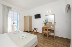 a bedroom with a bed and a desk and a mirror at Mare Naxia Hotel in Naxos Chora