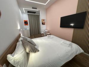 a bedroom with a white bed with a flat screen tv at Alloggio degli Eroi by LocazioniOK in Mola di Bari