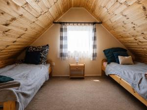 two beds in a attic bedroom with a window at AGROTURYSTYKA POD ŚNIEŻNĄ in Bystrzyca Kłodzka