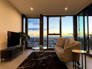 a living room with a couch and a tv at Luxurious City View with Gym Pool Parking Playground in Sydney