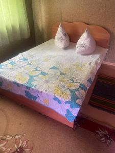 a small bed with a floral comforter and two pillows at Домики in Borovoye