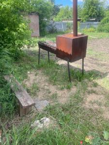 an old stove and a wooden bench in a field at Домики in Borovoye