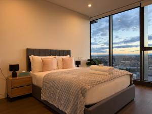 a bedroom with a bed and large windows at Luxurious City View with Gym Pool Parking Playground in Sydney