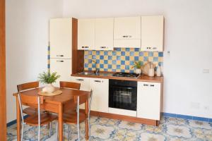 a kitchen with white cabinets and a wooden table with chairs at Maridea - Chiaia di Luna in Ponza