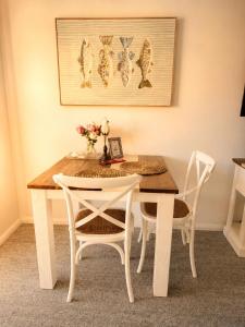 a dining room table with two white chairs and a table with flowers at Newly Restyled Resort Studio Oaks Pacific Blue in Salamander Bay +3 photos