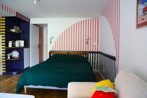 a bedroom with a green bed and a couch at Stripe Studio in Bonne-sur-Ménoge