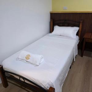 a bed with white sheets and white towels on it at Sunflower Residences Capitol formerly mayflower inn in Cebu City