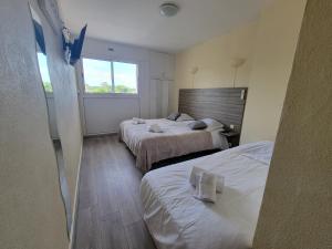 a hotel room with two beds and a window at Océan et Forêt in Les Mathes