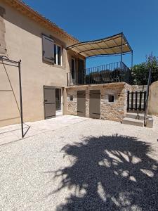 a building with a shadow of a tree on the ground at Le Mas Gabantelye in Saint-Paulet-de-Caisson