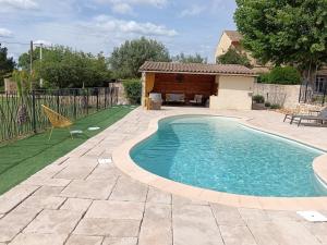 a swimming pool in a yard next to a house at Le Mas Gabantelye in Saint-Paulet-de-Caisson