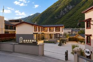 a house with a mountain in the background at Tuke Light Hotel Jiuzhaigou 途客轻居酒店九寨沟店 in Jiuzhaigou