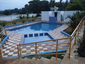 a large swimming pool with a wooden rail around it at Nilavoor in Yelagiri