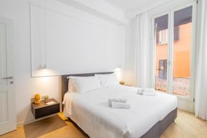 a white bedroom with a large bed and a window at Mamma Mia Holidays - Dimore Maggiori in Bologna