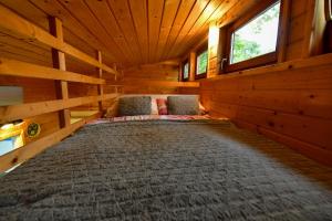 a large bed in a log cabin with two chairs at Tiny House Grabovac in Rakovica