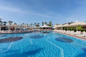a large swimming pool with chairs and umbrellas at Orange County Belek in Belek