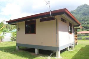a small house with a red roof on the grass at Moorea Lodge Arii in Afareaitu