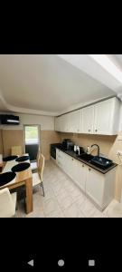 a kitchen with white cabinets and a table and a dining room at Apartament Catrys in Brezoi