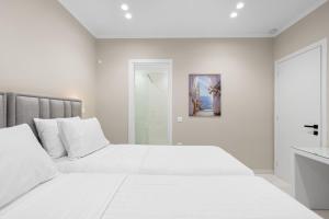 a white bedroom with two beds and a mirror at Meganisi Villas Royal in Meganisi +16 photos