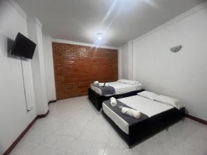 two beds in a room with a brick wall at Casa Vacacional San Gil Santander in San Gil