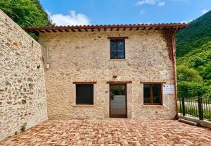 a large stone building with a brick driveway at Casa Vacanze Partenzi in Vallo di Nera