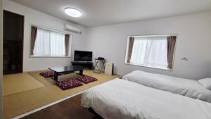ein Zimmer mit zwei Betten und einem Tisch darin in der Unterkunft Atria CHIKURA in Minamiboso