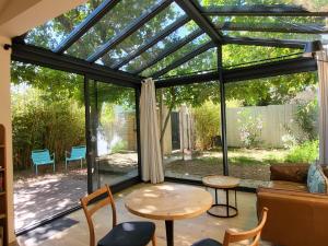 a conservatory with a glass door and a table and chairs at Le mazet des amants, cabane en bois avec jacuzzi privatif in Avignon