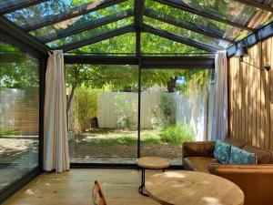 a glass conservatory with a couch and a table at Le mazet des amants, cabane en bois avec jacuzzi privatif in Avignon +18 photos