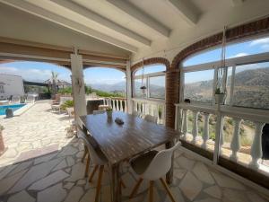 a dining room with a table and chairs and windows at Casira gastenkamers & Casitas, Viñuela, Andalucía in Viñuela