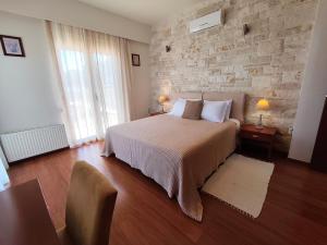 a bedroom with a bed and a stone wall at Villa Tholos Crete in Kavoúsion