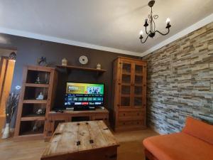 a living room with a tv and a wooden table at Villa Perdomo in Las Palmas de Gran Canaria