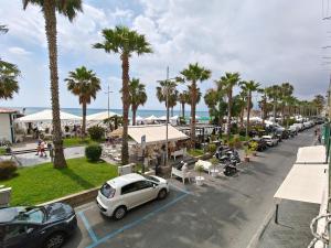 a white car parked in a parking lot with palm trees at Garibaldi 39 in Loano