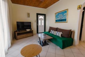 a living room with a green couch and a flat screen tv at MARINA in Perama