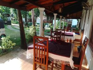 a group of four beds on a porch at Rio Lake Hotel Sigiriya in Habarana